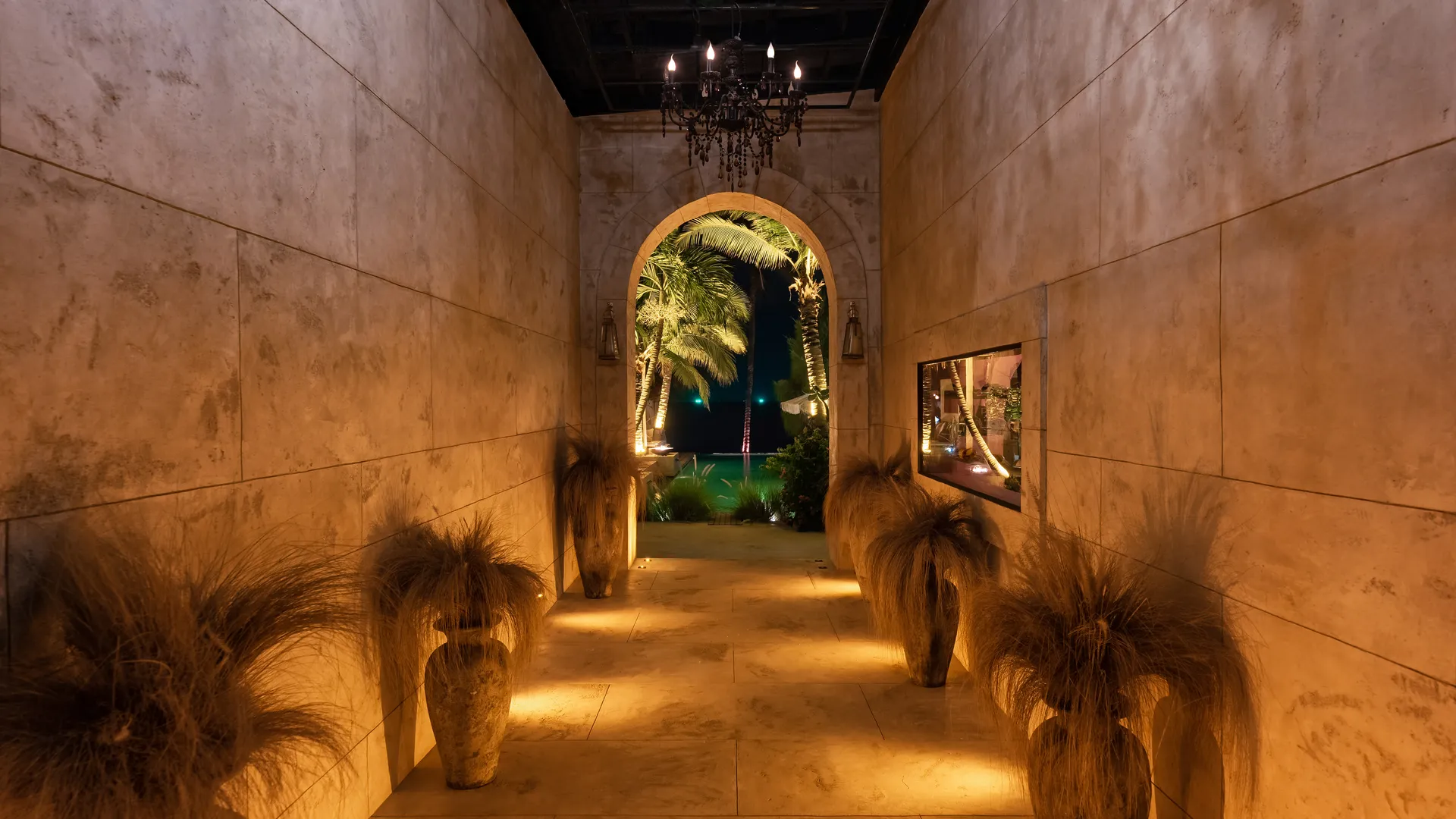 Honesty of Materials in Luxury Thai Villa Architecture Elegant stone corridor at Villa Odyssey in Bangrak, Koh Samui, Thailand, with warm lighting, natural textures, and an arched view of palm trees and the tropical night.