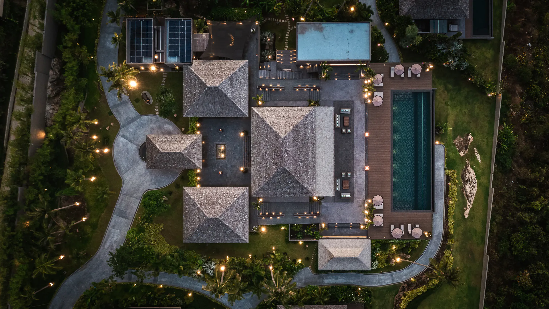 Aerial night view of Shankara Estate Koh Samui luxury wedding venue showing illuminated traditional Thai pavilions, multiple swimming pools, and landscaped gardens ideal for hosting 100+ guest celebrations.